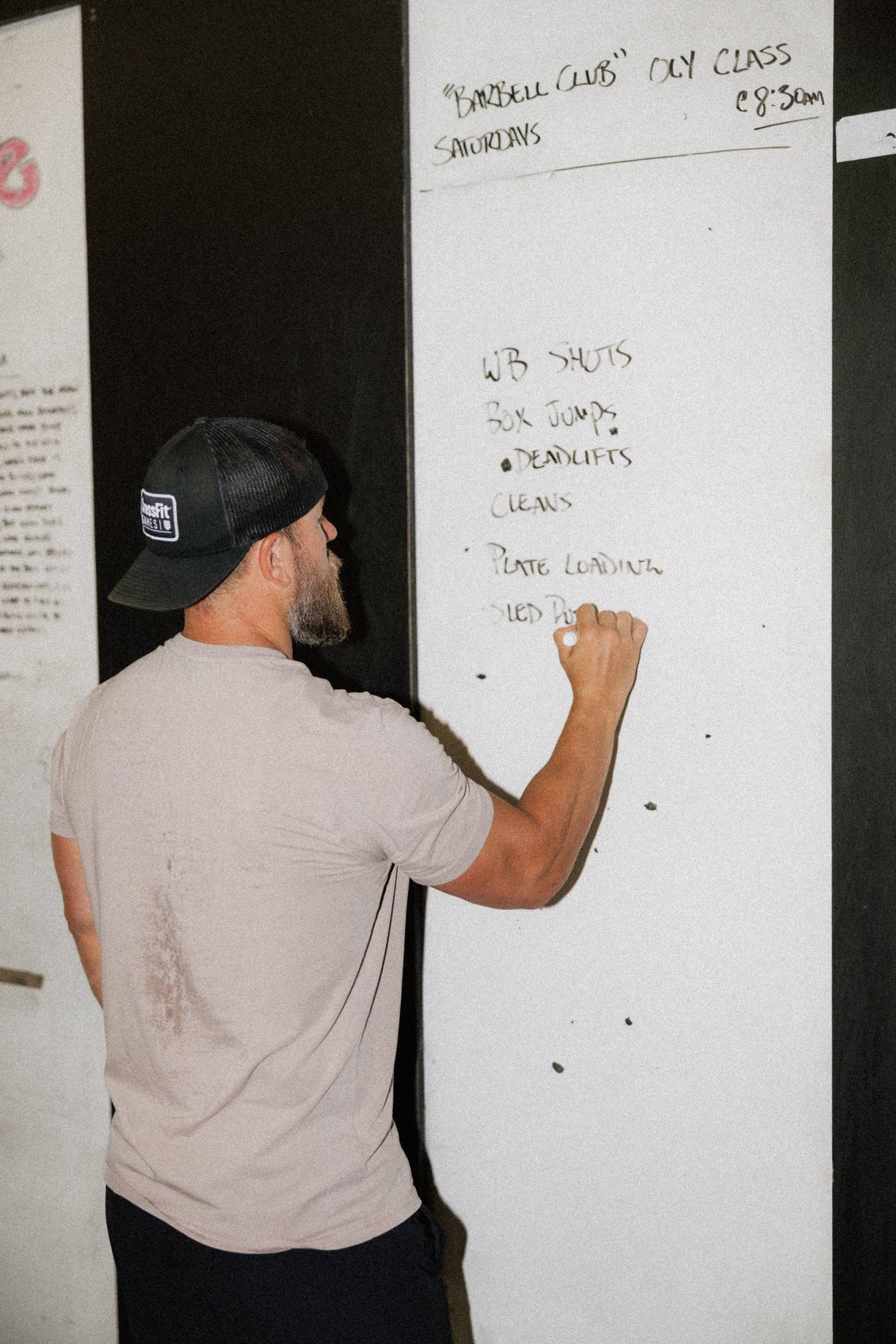 A coach writing the day's workout on the whiteboard